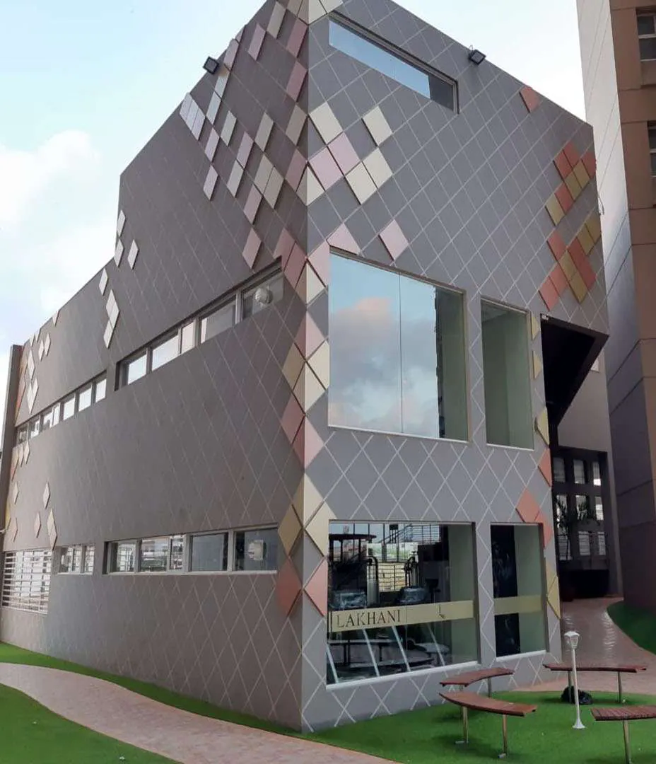 The residents’ clubhouse, its facade patterned in diamond tiles, with the LAKHANI name on the glass