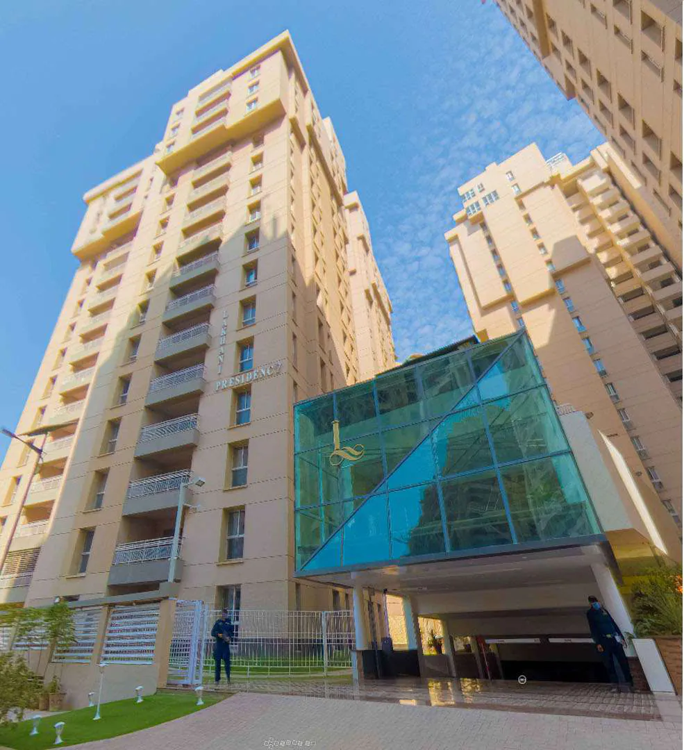 The glass entrance canopy at the foot of the Lakhani Presidency towers