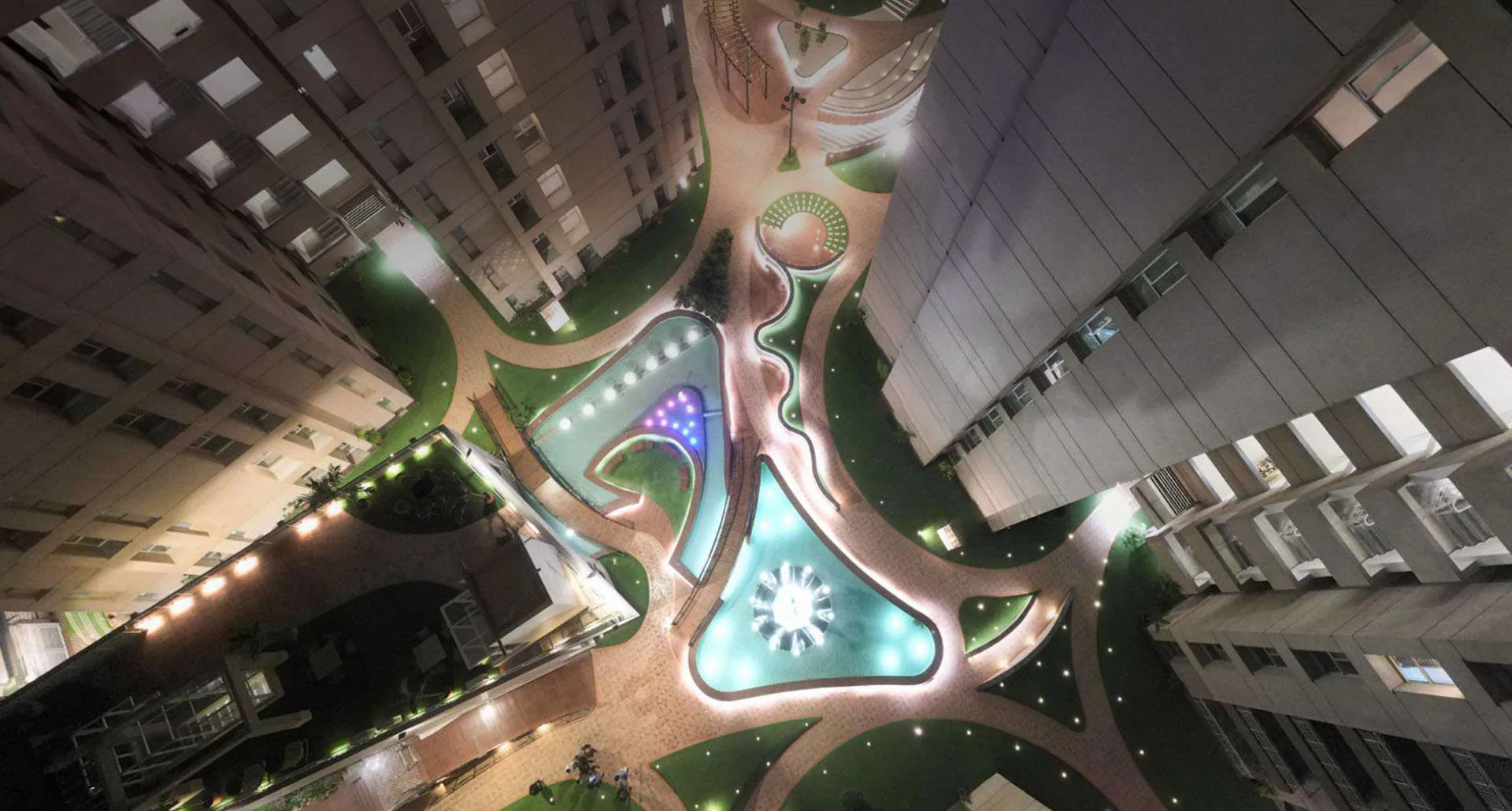 Night view of the landscaped court from above, pathways and pools lit